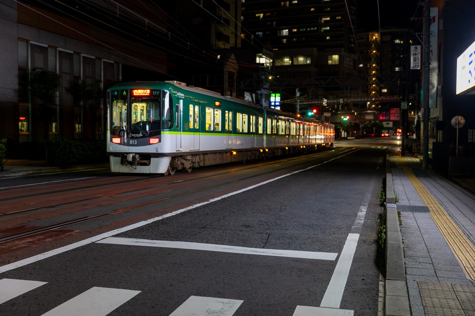 夜、道の真ん中を走る路面の電車